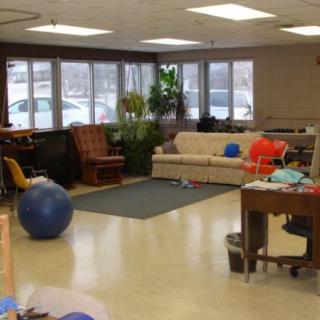 A cozy living room with comfortable seating, a table, and an exercise ball.