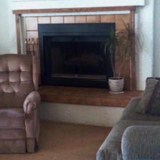 A cozy living room with a fireplace, armchair, and sofa.