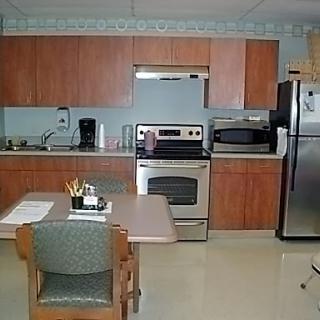 A modern kitchen featuring wooden cabinets, stainless steel appliances, and a small dining area.