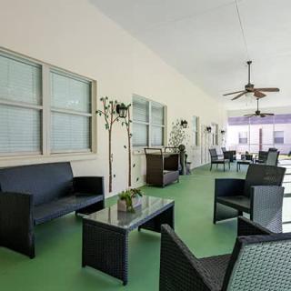 A modern outdoor patio with comfortable seating, green flooring, and a ceiling fan for ventilation.