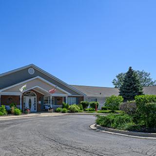 A well-maintained suburban building with lush landscaping and a circular driveway on a clear day.