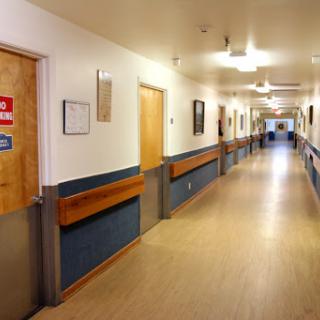 A clean and well-lit hospital hallway with doors leading to different rooms.