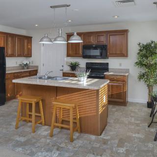 Modern kitchen with wooden cabinets, a central island with stools, and stainless steel appliances.