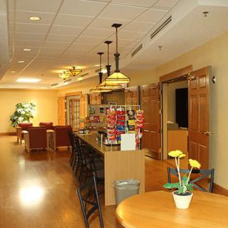 A cozy kitchen and lounge area with seating, wooden flooring, and warm lighting.