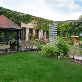 A serene garden space featuring lush green grass, a gazebo, and colorful flowers.