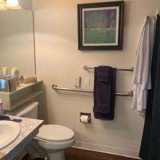 A cozy bathroom with a toilet, sink, and mirror, featuring artwork and neatly arranged towels.