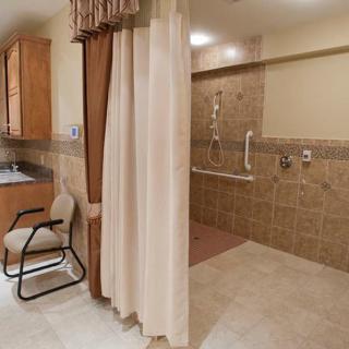 An accessible bathroom featuring a shower with handrails and a curtain.