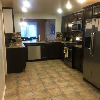 A modern kitchen with dark cabinets and stainless steel appliances.