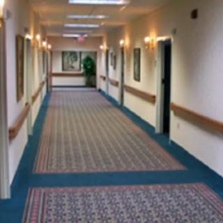 A long, well-lit hallway with patterned carpet and framed pictures on the walls.