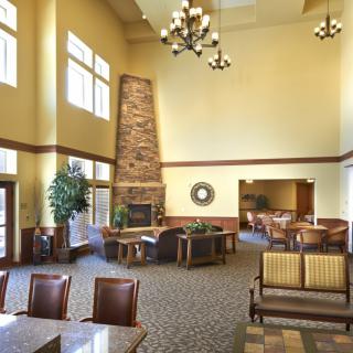 A spacious lobby featuring a stone fireplace, multiple seating areas, and large windows allowing natural light to brighten the room.
