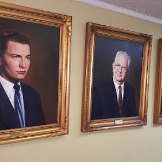 Three formal portraits of men displayed in ornate frames.