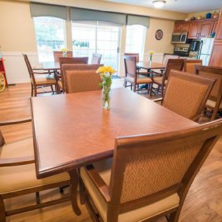 A cozy dining area with several tables and chairs, featuring a view into the kitchen.