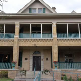 A historic two-story house with a large porch and balcony.