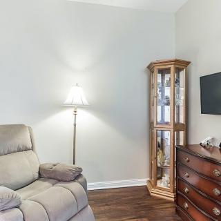 A cozy living room corner with an armchair, lamp, and display cabinet.