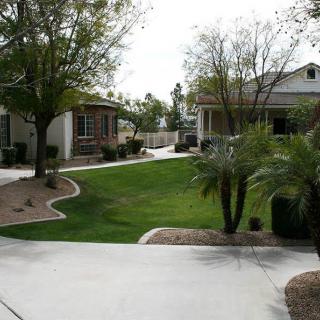 A suburban residential area with houses, a well-maintained lawn, and surrounding trees.
