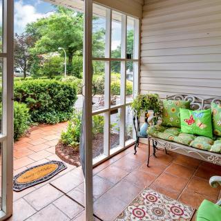 A cozy porch with decorative seating and a garden view on a sunny day.