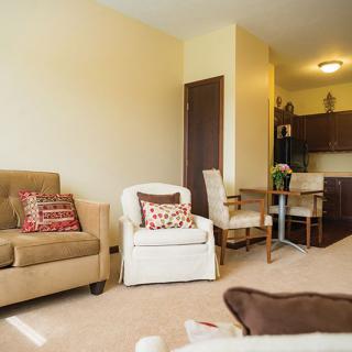 A cozy living room featuring a sofa, armchairs, and an open kitchen area.