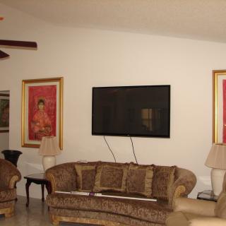A cozy living room with a large sofa, television, and framed artwork on the walls.