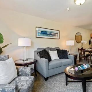 A cozy living room with a sofa, armchairs, coffee table, and dining area.