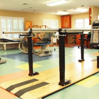 A rehabilitation room with parallel bars and exercise equipment.