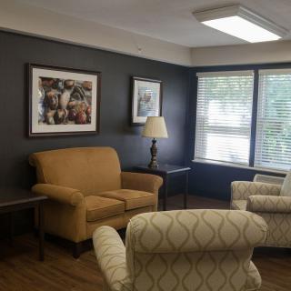 A cozy living room with a sofa, chairs, and framed artwork on the wall.
