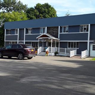 A two-story residential building with a vehicle parked in front.