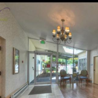 A well-lit lobby with a chandelier, featuring a waiting area and glass doors leading outside.