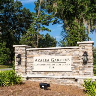 Entrance sign for Azalea Gardens Cemetery surrounded by trees.