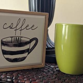 A cozy setup with a 'coffee time' sign and a green mug on display.