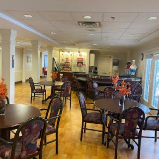 A spacious dining area set up for community gatherings, featuring tables and chairs adorned with floral decorations.