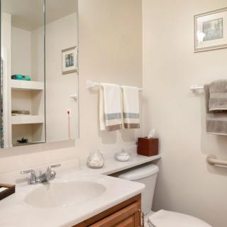 A clean, well-organized bathroom with a sink, mirror, and neatly arranged towels.