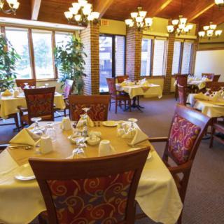 A cozy restaurant interior featuring neatly set tables and comfortable chairs under warm lighting.