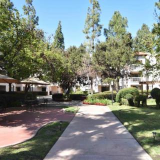 A well-maintained apartment complex with a pathway surrounded by trees and greenery.