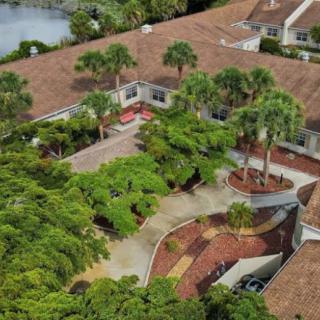 Aerial view of a residential property with extensive landscaping and palm trees.