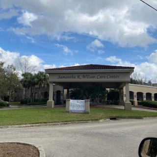 A view of a commercial building under a partly cloudy sky, featuring its entrance and signage.