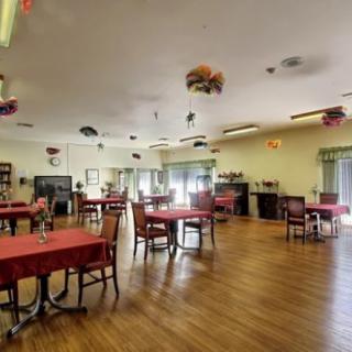 A spacious dining room with neatly arranged tables and chairs, featuring decorative elements and warm lighting.