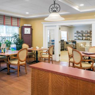 A cozy dining room with elegant chairs and tables, featuring warm lighting and wooden flooring.