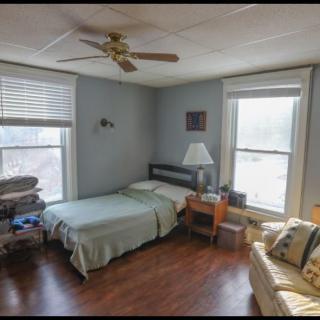A cozy bedroom with a bed, nightstand, and ceiling fan.