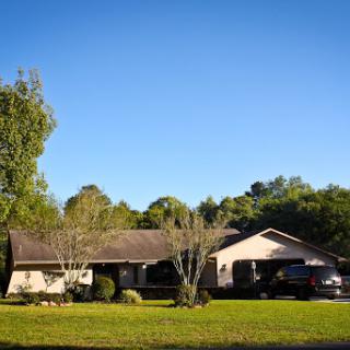 A serene suburban home surrounded by lush greenery under a clear blue sky.