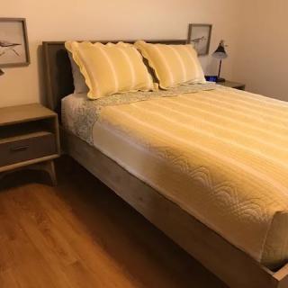 A neatly made bed with striped pillows and a matching quilt in a cozy bedroom.
