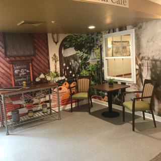 A cozy indoor cafe setting with a decorative wall mural and seating area.