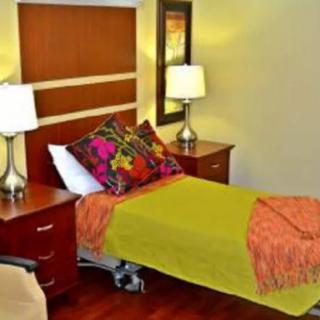 A cozy bedroom with a single bed, vibrant decor, and wooden flooring.