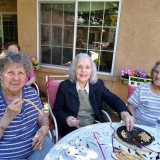 A group of elderly women enjoying a social gathering outdoors with snacks.
