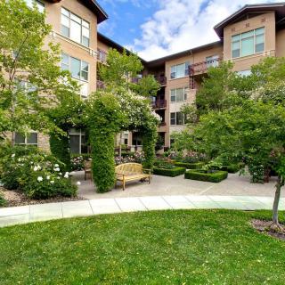 A peaceful garden area surrounded by an apartment complex with lush greenery and well-maintained landscaping.