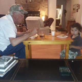 A touching moment at the dinner table, sharing a meal and conversation between generations.