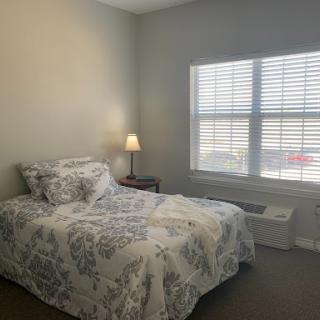 A cozy and well-lit bedroom featuring a comfortable bed and a bedside lamp.