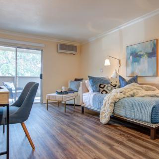 A modern open-plan apartment featuring a combined living and bedroom area with stylish furnishings and wood flooring.