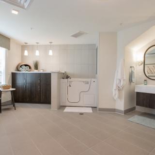 A modern bathroom with an accessible bathtub, elegant sink, and stylish mirror under soft lighting.