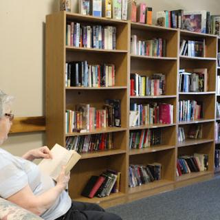 A person enjoying a book in a cozy library setting surrounded by books.