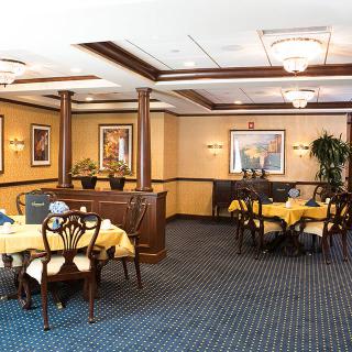 A well-decorated dining room with multiple tables and chairs, adorned with artwork on the walls.